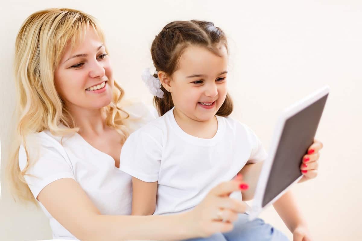 mom and daughter smiling looking at tablet