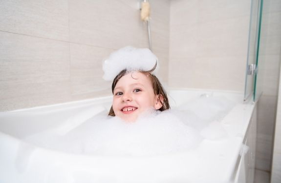 child in bubble bath with bubble on head