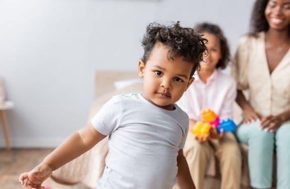 Toddler boy with mom in the background