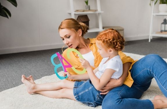 Mom and daughter sitting on floor playing