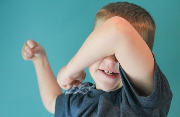 Boy covering his eyes and looking like he's about to hit someone