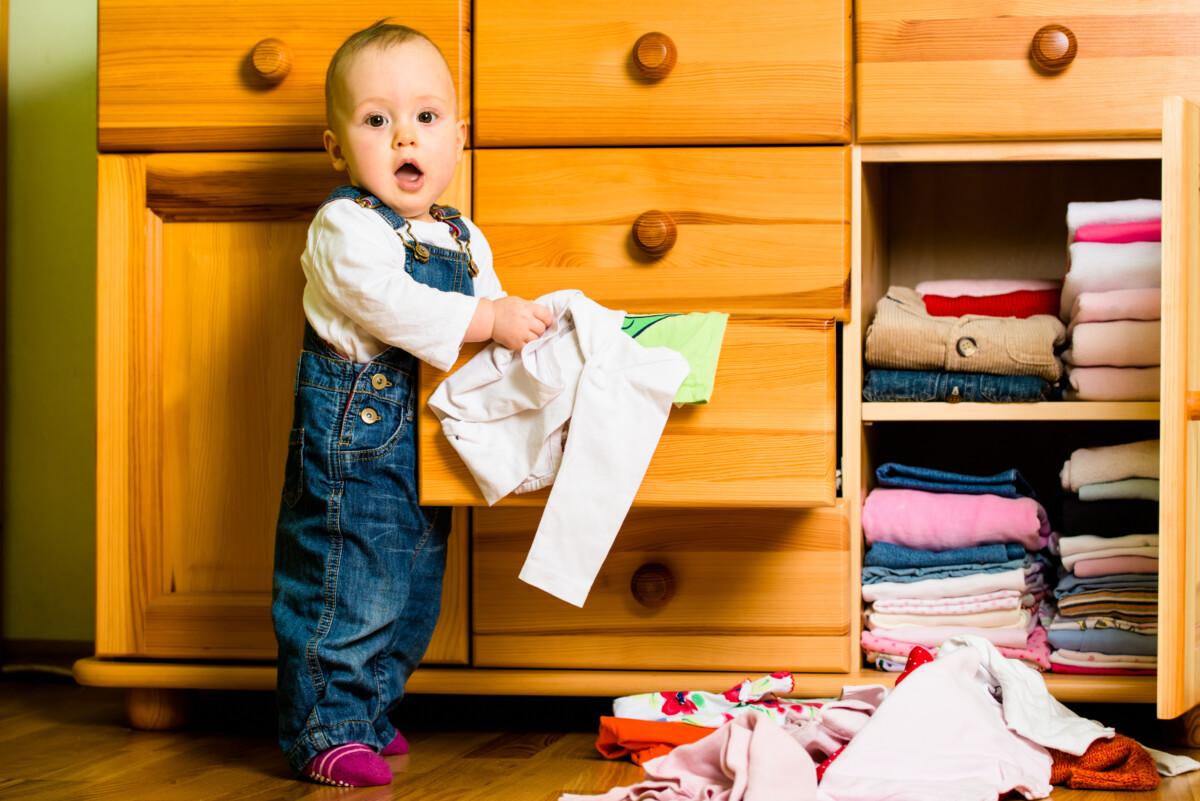 baby standing and pulling clothes out of dresser for the article titled how to discipline a 1 year old with gentle parenting