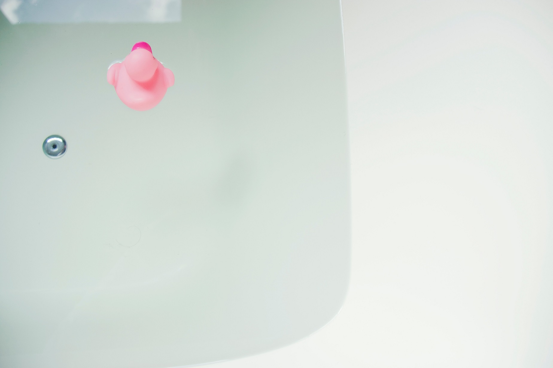 Bath with water and pink rubber duck - for an article to learn about giving a sensory sensitive child a bath