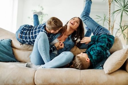 mom and two kids on the couch playing and laughing