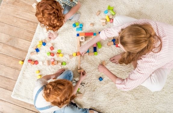 over head view of mom and two kids playing together on the floor
