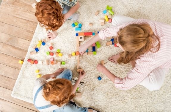 over head view of mom and two kids playing together on the floor