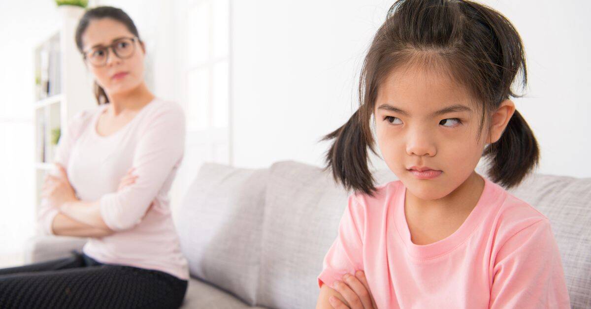 Mother and child sitting on couch looking cranky